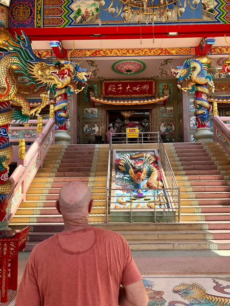 Tour guest admiring the ornate dragon statues and colorful architecture of Naja Chinese shrine