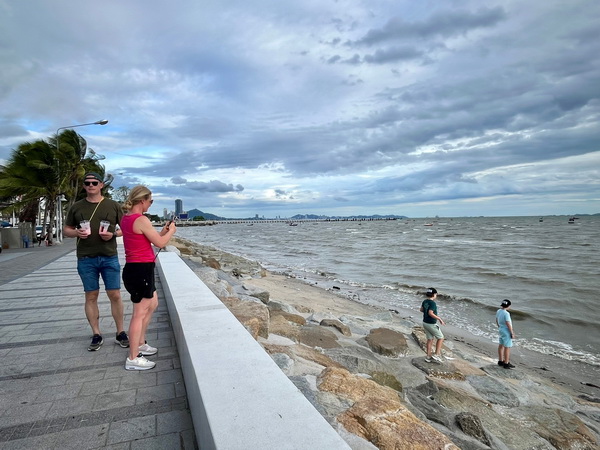 Family enjoying the scenic Bang Saen coastline with ocean waves and rocky shore