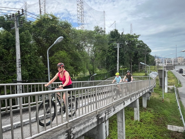Cyclists riding across an elevated bridge on the Tour de Bang Saen coastal route