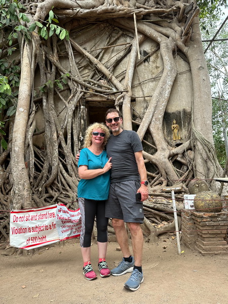 Couple posing in front of an ancient temple overgrown by tree roots on the floating market bike tour