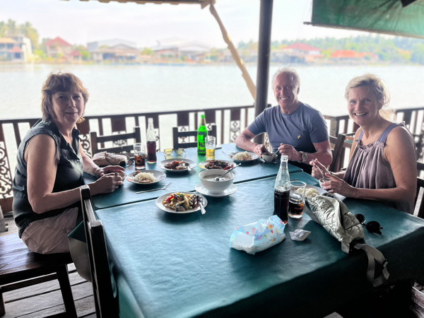 Tour guests enjoying a delicious lunch at a riverside restaurant during the floating market tour