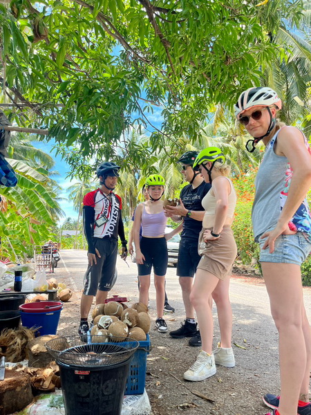 Tour group learning about harvesting coconuts in a coconut plantation on the train and floating market tour