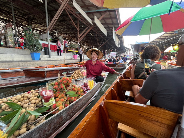 Vendor selling fresh fruit from her boat at the floating market during the train and floating market tour