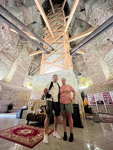 Couple standing inside the historic Wat Prayun chedi with its impressive wooden support structure