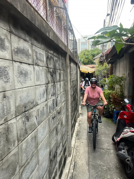 Cyclist navigating a narrow back alleyway between old concrete walls during the Twilight Sunset tour
