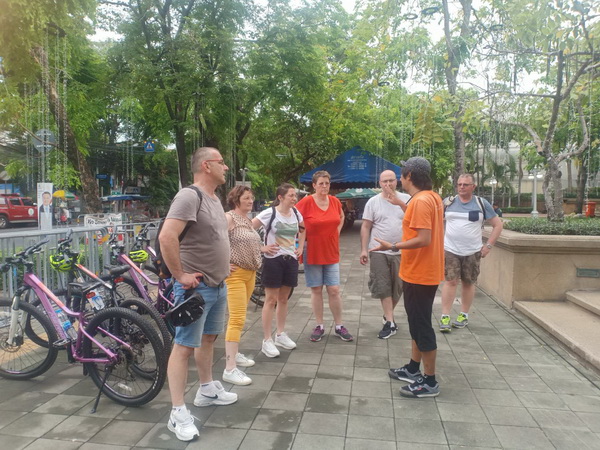 Tour guide briefing a small group of cyclists in a lush historical park before the Twilight Sunset ride