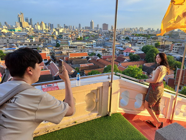 Visitor taking photos of the panoramic Bangkok cityscape from the top of Golden Mountain temple at sunset
