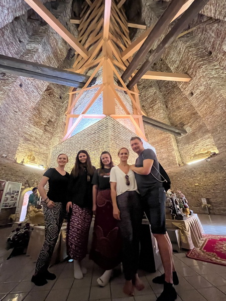 Group of cyclists exploring the interior of Wat Prayun chedi with ancient brick walls and wooden beams