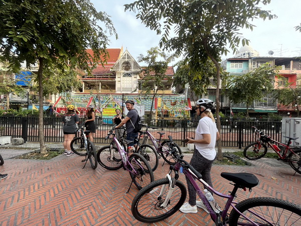 Cycling group getting ready at the start of the tour near a temple with colourful murals