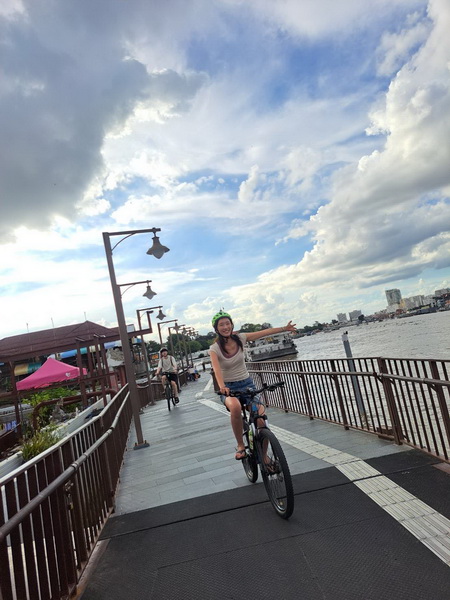 Cyclist riding along the scenic Chao Phraya river promenade during the golden hour