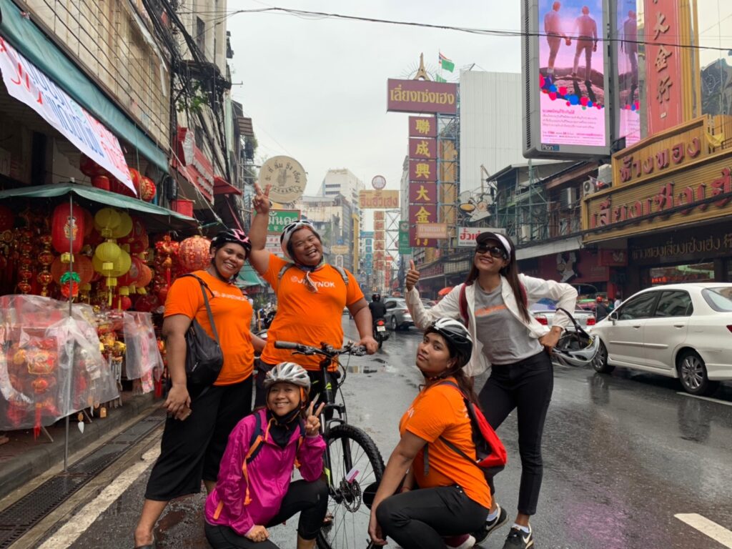 Small group of tourists enjoying Bangkok bicycle tour through local neighborhood