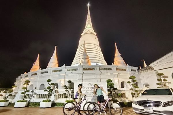Cyclists riding through illuminated Bangkok streets at night on a guided bicycle tour