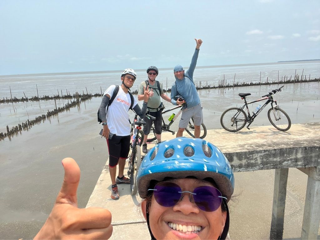 Cyclists at a traditional Thai fishing village on the Gulf of Thailand shore
