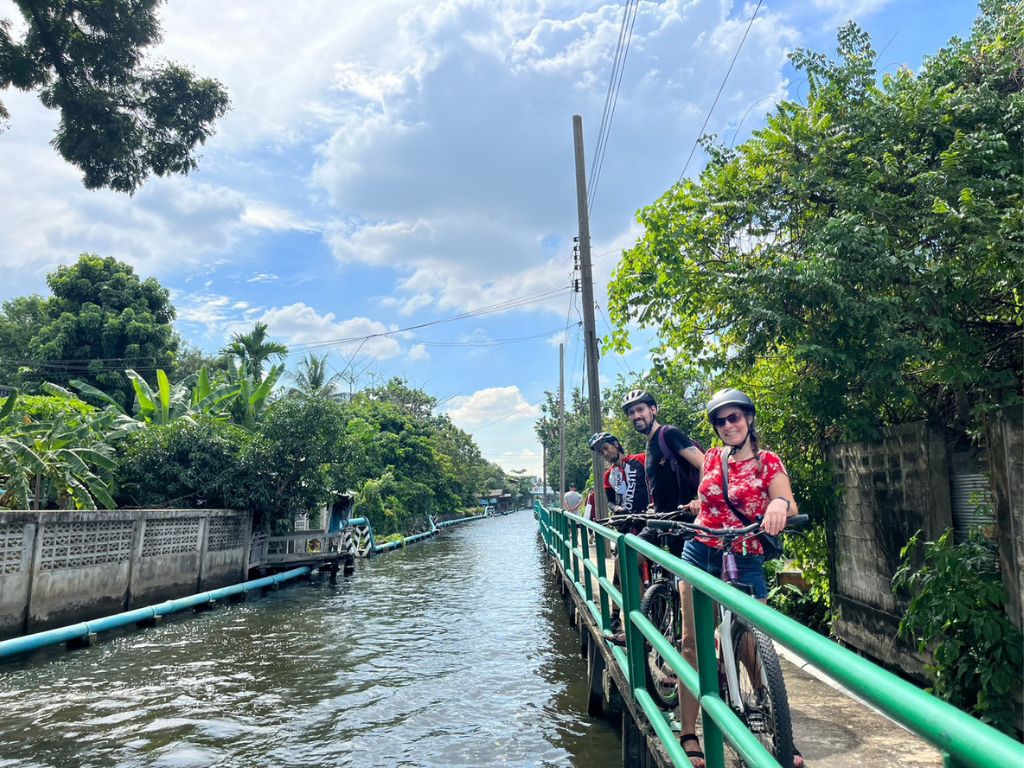 Cyclists riding along shaded Bangkok canals near Taling Chan floating market