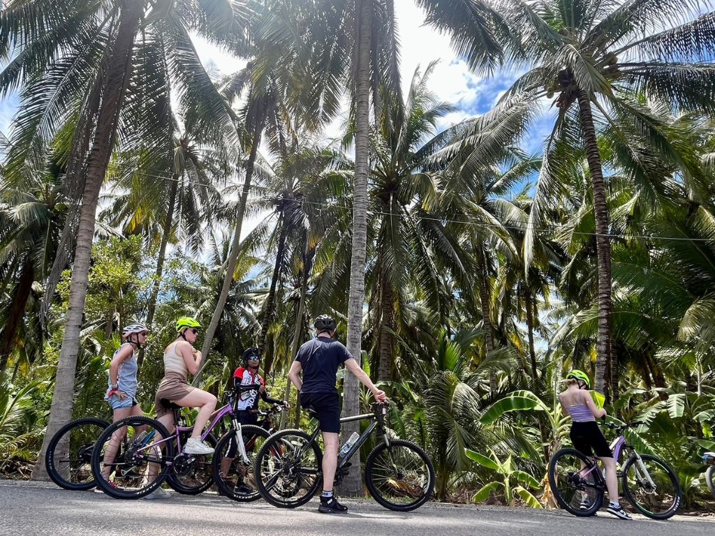 Cycling through lush coconut plantations and fruit orchards on the Train Market and Floating Markets bike tour